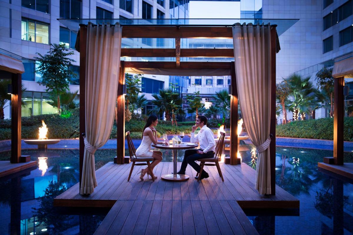a man and a woman sitting at a table on a patio at JW Marriott Hotel New Delhi Aerocity in New Delhi a man and a woman sitting at a table on a patio at JW Marriott Hotel New Delhi Aerocity in New Delhi