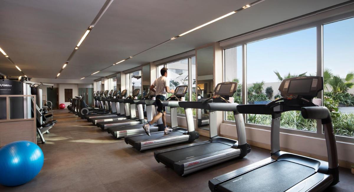 a room with a row of treadmills in a gym at JW Marriott Hotel New Delhi Aerocity in New Delhi a room with a row of treadmills in a gym at JW Marriott Hotel New Delhi Aerocity in New Delhi