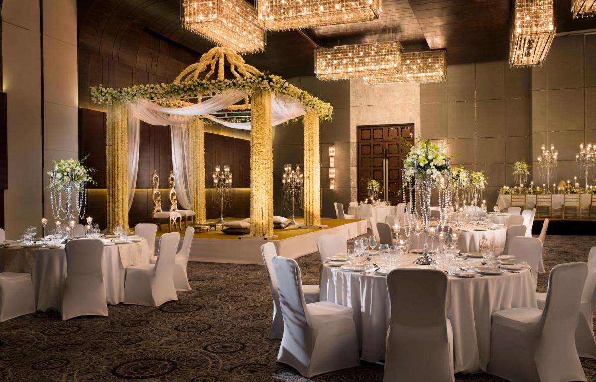 a banquet room with white tables and chairs and chandeliers at JW Marriott Hotel New Delhi Aerocity in New Delhi a banquet room with white tables and chairs and chandeliers at JW Marriott Hotel New Delhi Aerocity in New Delhi