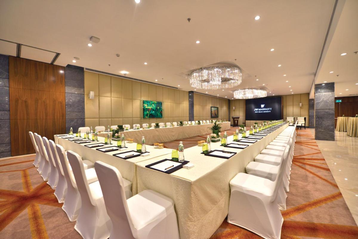 a large conference room with a long table and white chairs at JW Marriott Hotel New Delhi Aerocity in New Delhi a large conference room with a long table and white chairs at JW Marriott Hotel New Delhi Aerocity in New Delhi