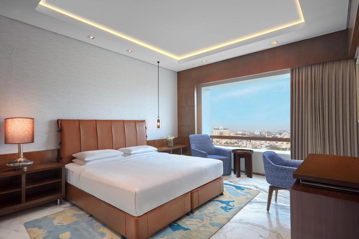 a bedroom with a bed and a desk and a window at Hyatt Regency Chennai in Chennai