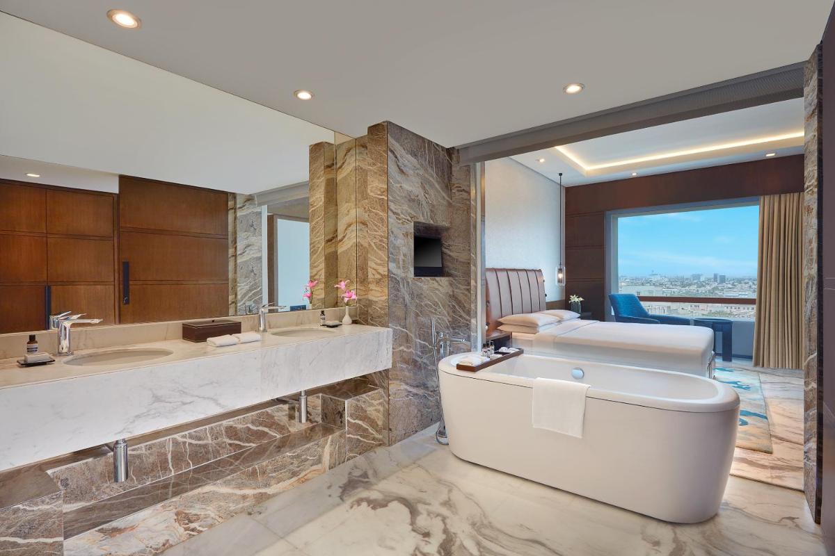 a bathroom with a tub and two sinks and a bed at Hyatt Regency Chennai in Chennai