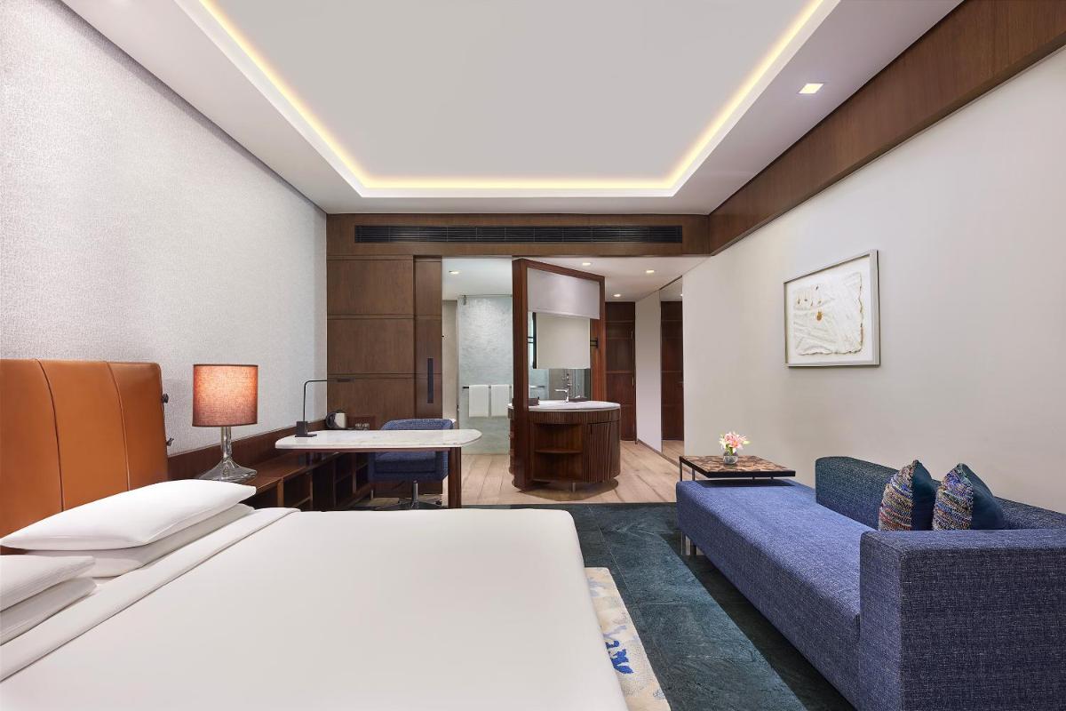 a hotel room with a bed and a blue couch at Hyatt Regency Chennai in Chennai
