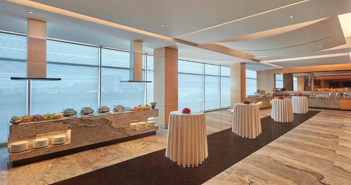 a lobby with three white tables and a bar at Hyatt Regency Chennai in Chennai