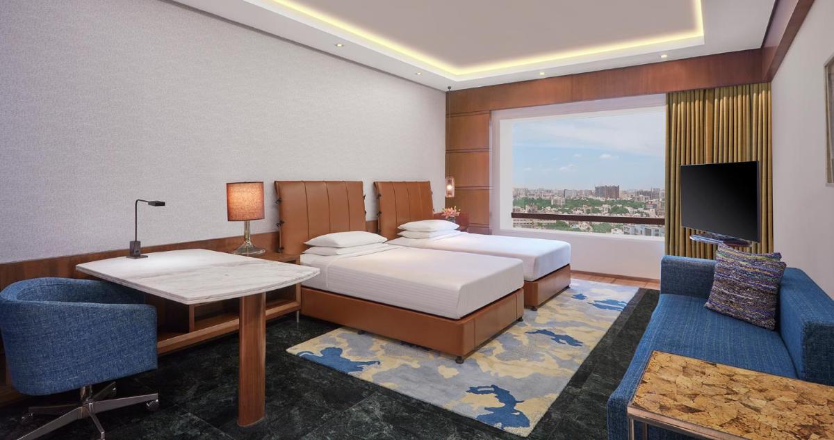 a bedroom with a bed and a desk and a tv at Hyatt Regency Chennai in Chennai