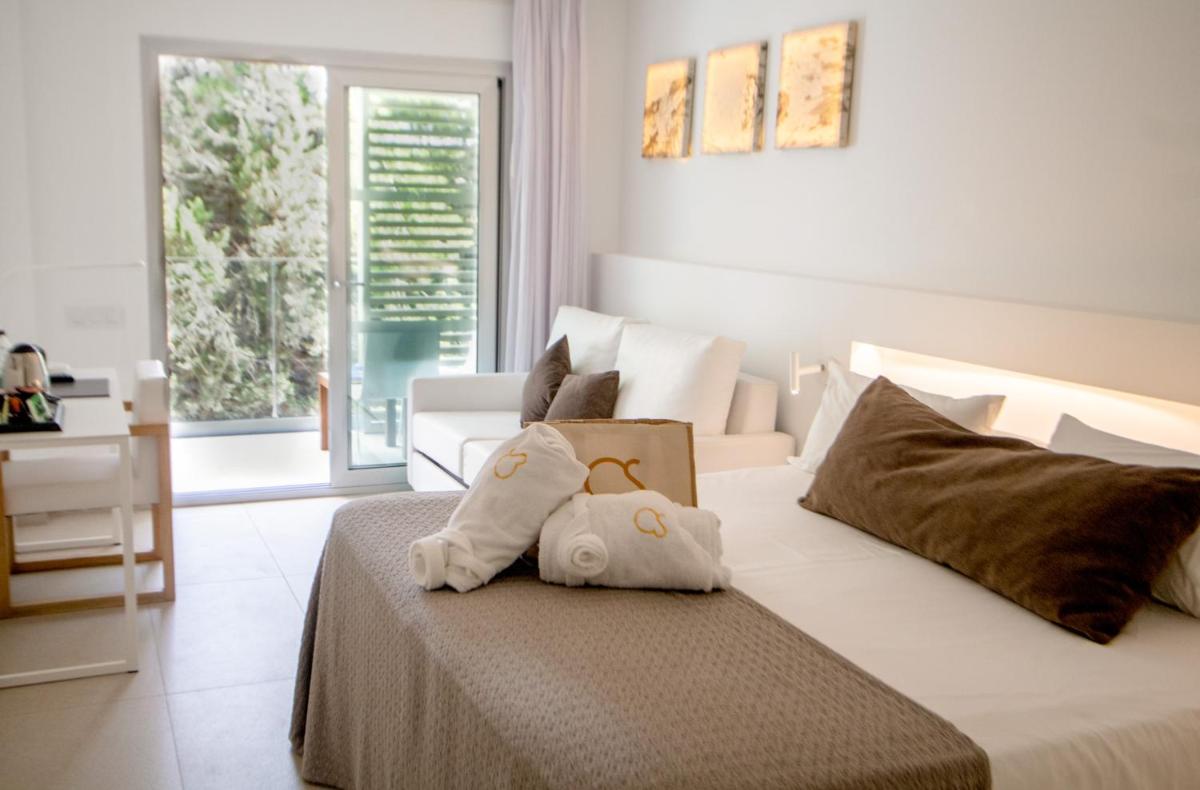 Un dormitorio blanco con una cama con una caja. en Hotel Cala Saona & Spa, en Cala Saona