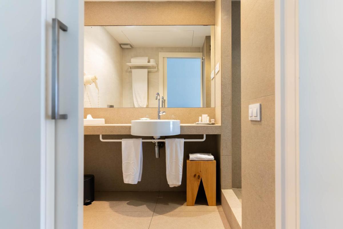 un baño con lavabo y espejo en Hotel Cala Saona & Spa, en Cala Saona