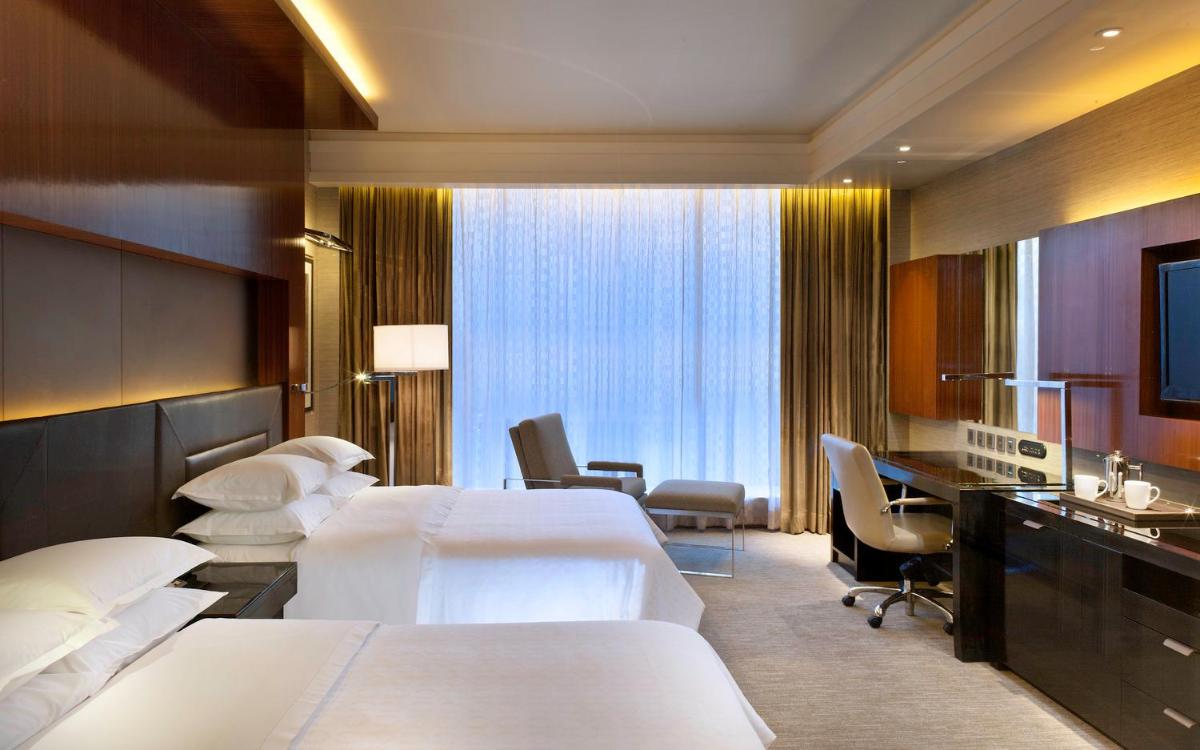 a hotel room with two beds and a desk at Sheraton Grand Bangalore Hotel at Brigade Gateway in Bengaluru