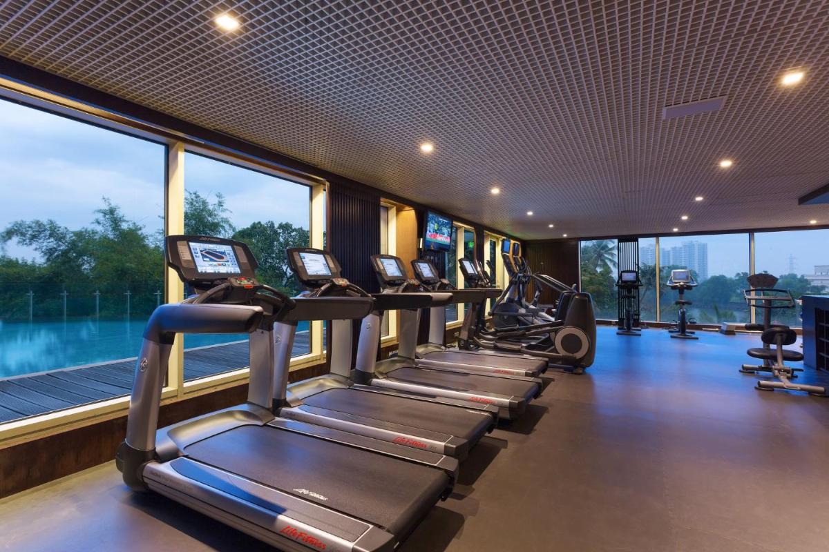 a row of treadmills in a gym with windows at Crowne Plaza Kochi by IHG in Cochin