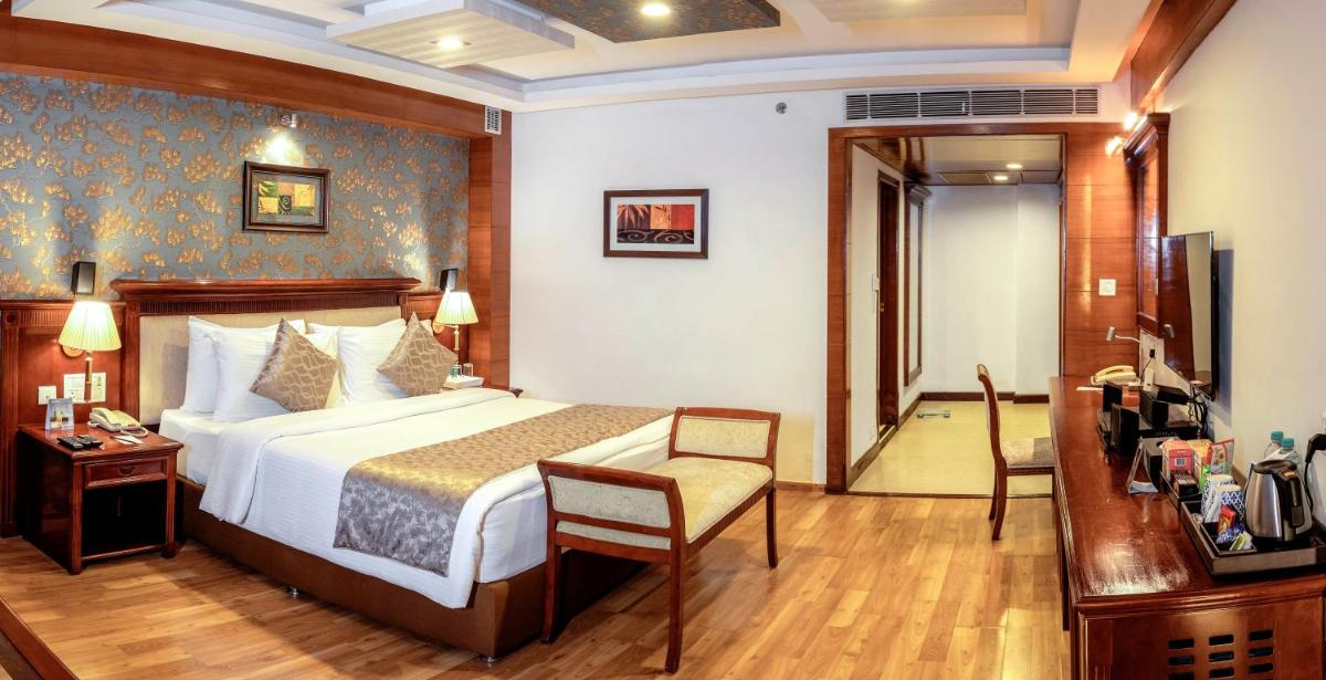 a bedroom with a bed and a table and a chair at Fortune JP Palace, Mysore - Member ITC Hotels' Group in Mysore