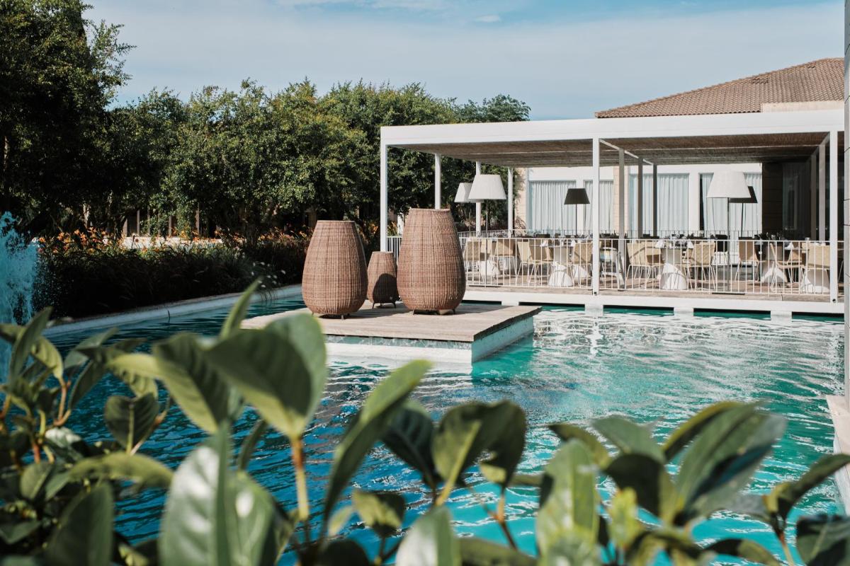 una piscina con dos sillas y una casa en Prinsotel La Dorada & Spa, en Playa de Muro