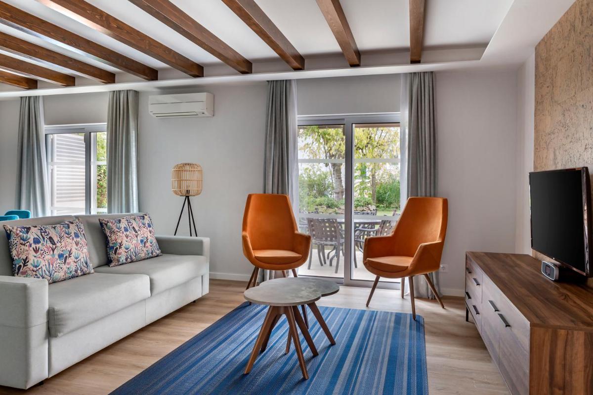 uma sala de estar com um sofá, cadeiras e uma TV em Vilar do Golf na Quinta do Lago