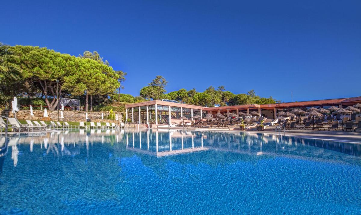 uma grande piscina de água com cadeiras e um edifício em Vilar do Golf na Quinta do Lago