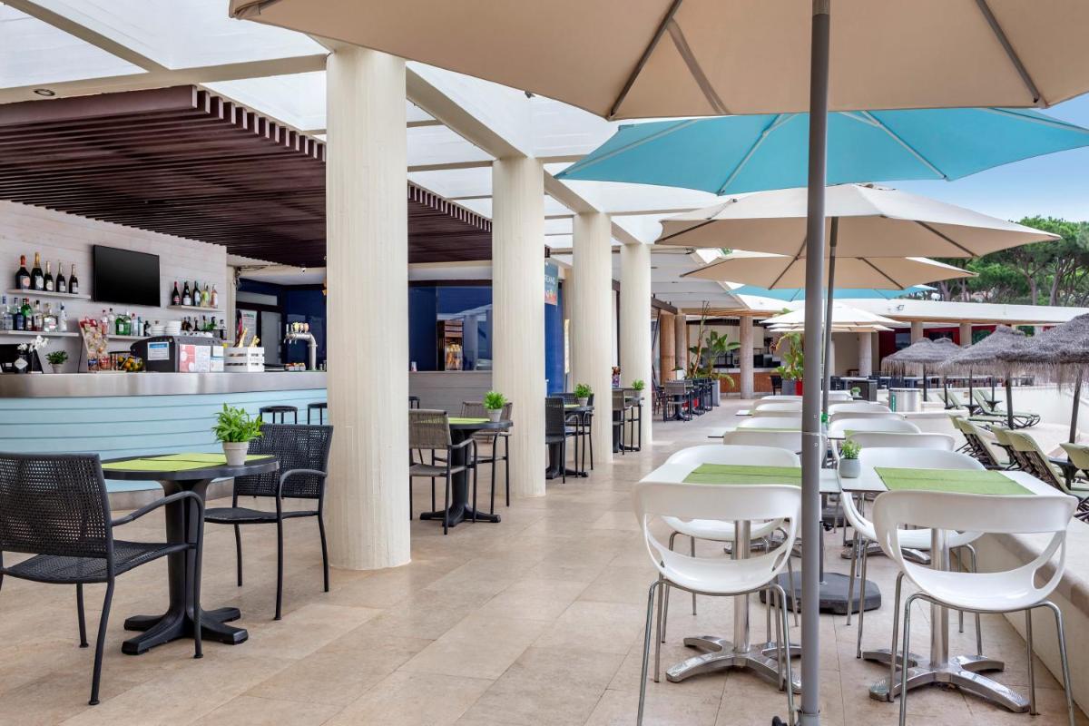 um restaurante com mesas e cadeiras com guarda-sóis em Vilar do Golf na Quinta do Lago