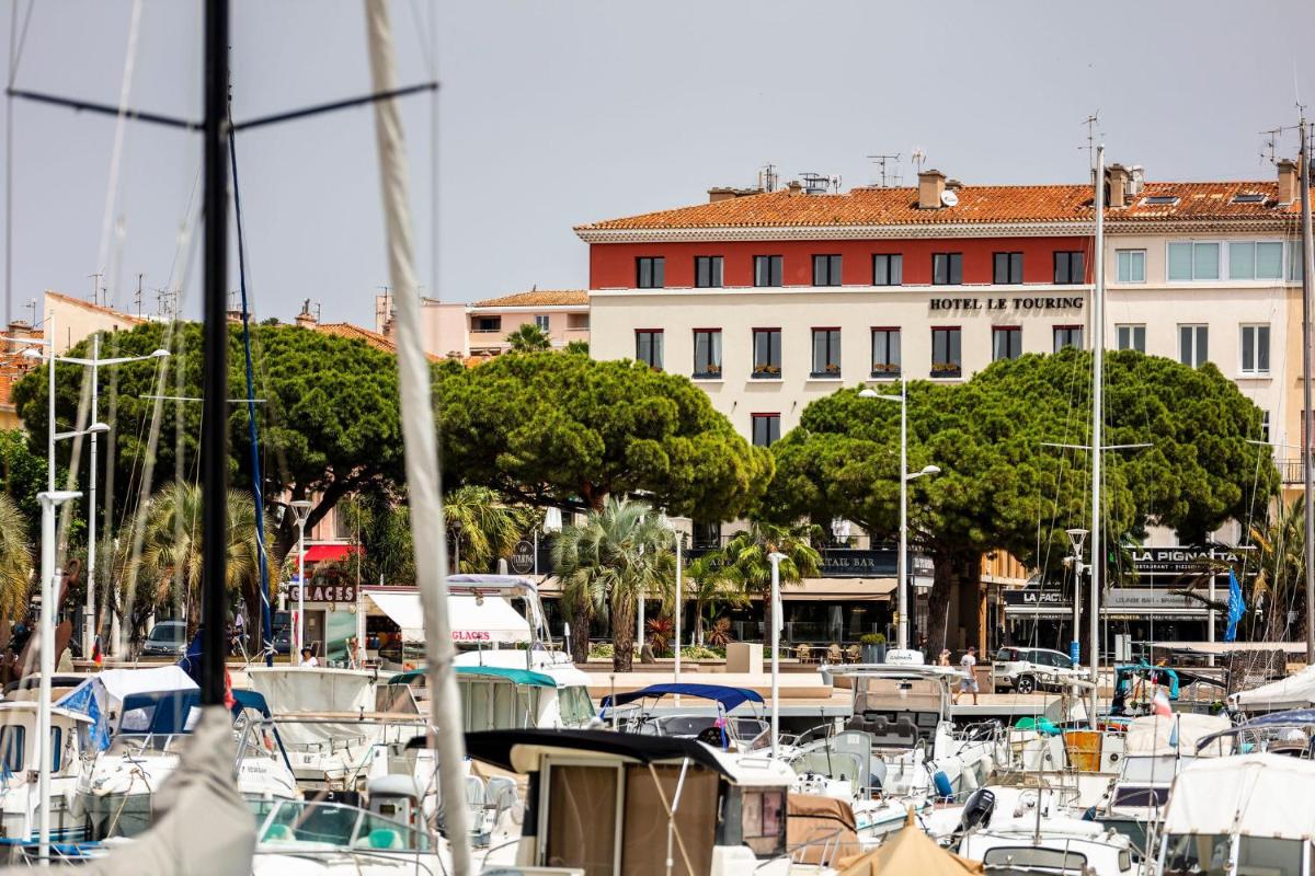 un groupe de bateaux amarrés dans un port avec un bâtiment dans l'établissement Hôtel Restaurant le Touring - Teritoria, à Saint-Raphaël