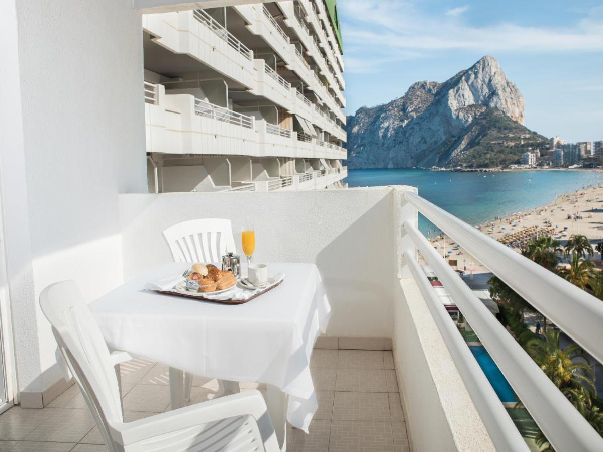 Una mesa y sillas en un balcón con vista al mar. en AR Roca Esmeralda & SPA Hotel, en Calpe