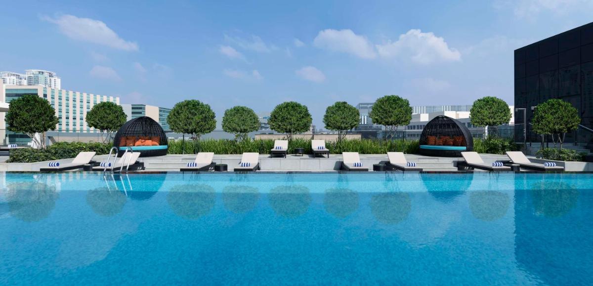 a large swimming pool with lounge chairs on a building at Hilton Bengaluru Embassy Manyata Business Park in Bengaluru
