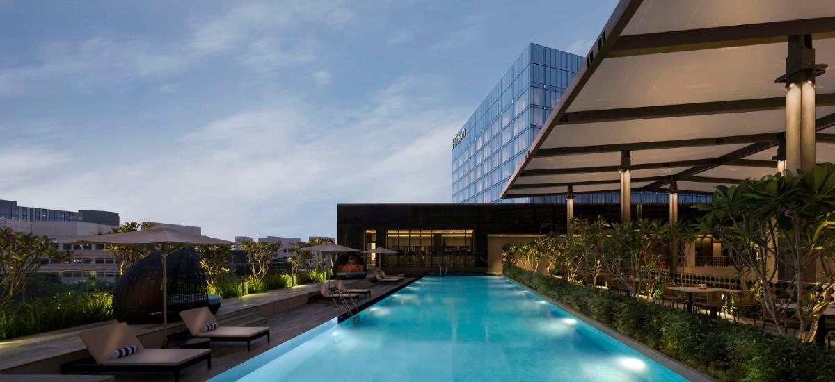 a swimming pool with lounge chairs and a building at Hilton Bengaluru Embassy Manyata Business Park in Bengaluru