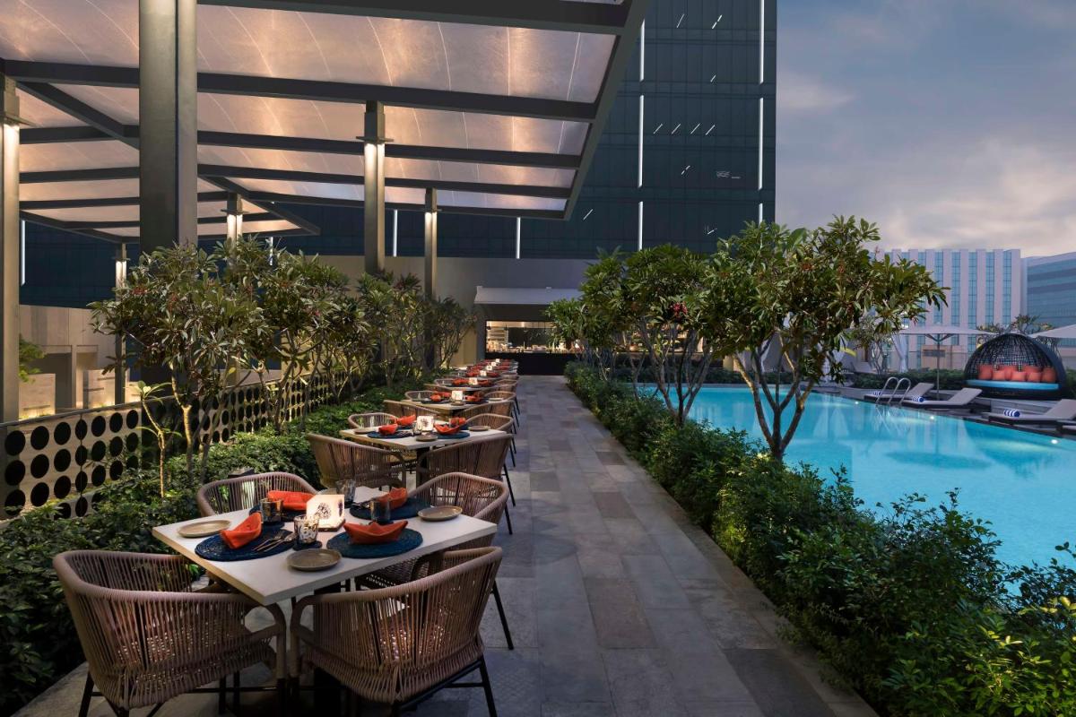 a row of tables and chairs on a building with a pool at Hilton Bengaluru Embassy Manyata Business Park in Bengaluru