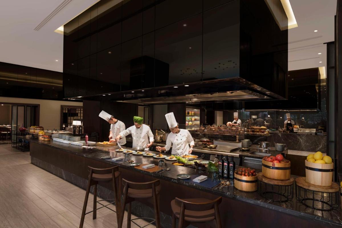 three chefs are preparing food in a kitchen at Hilton Bengaluru Embassy Manyata Business Park in Bengaluru