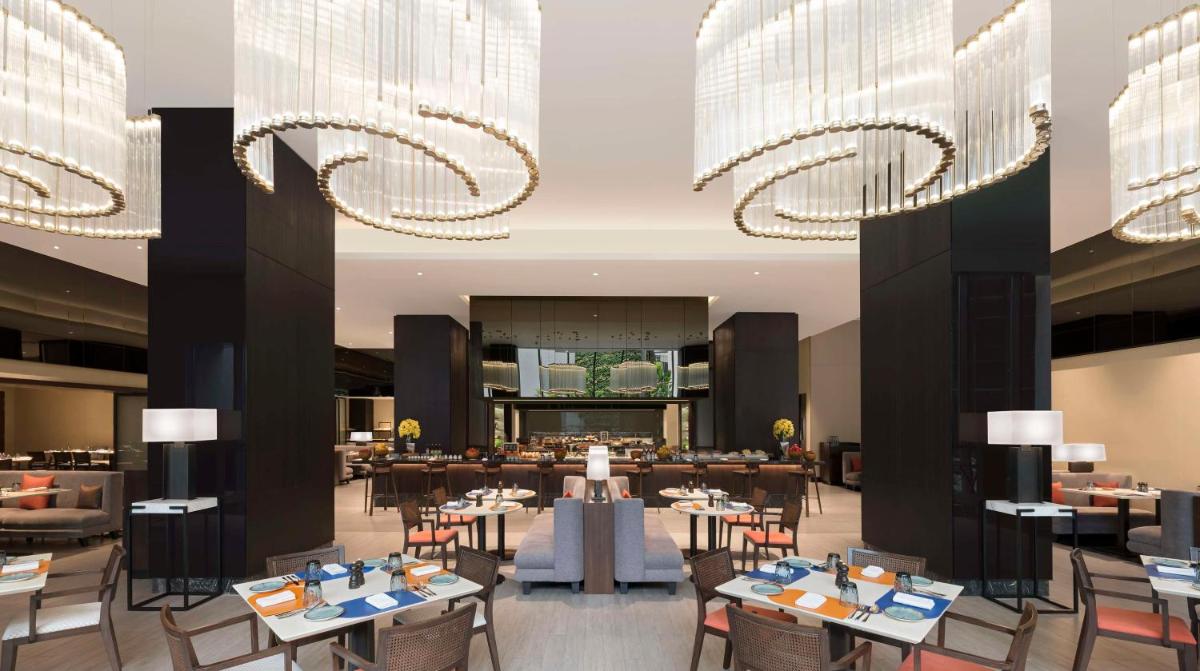 a restaurant with tables and chairs and chandeliers at Hilton Bengaluru Embassy Manyata Business Park in Bengaluru