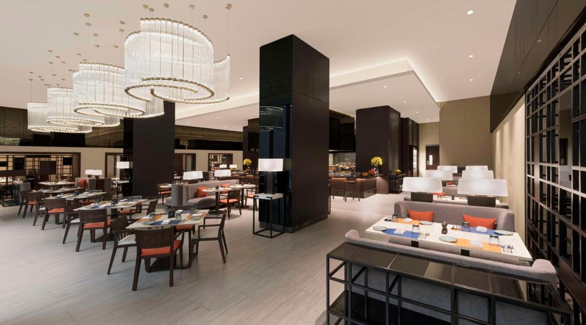 a restaurant with tables and chairs and a chandelier at Hilton Bengaluru Embassy Manyata Business Park in Bengaluru