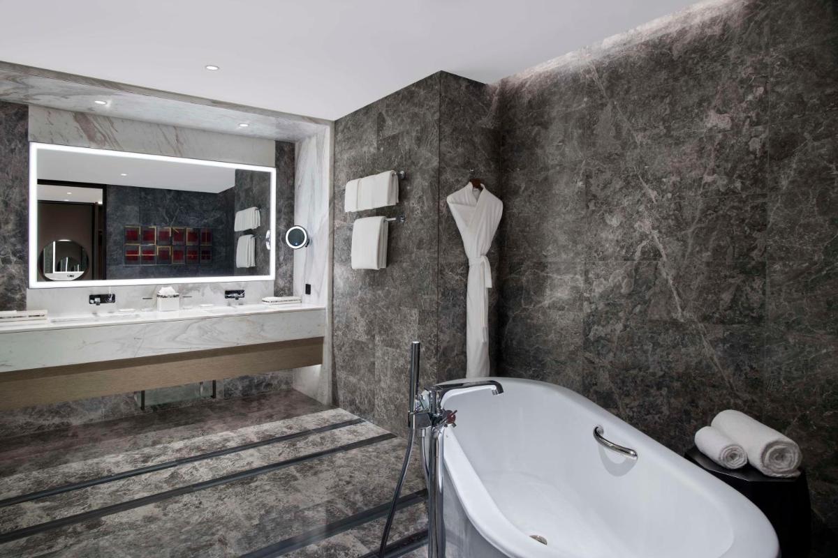 a bathroom with a tub and a sink and a mirror at Hilton Bengaluru Embassy Manyata Business Park in Bengaluru
