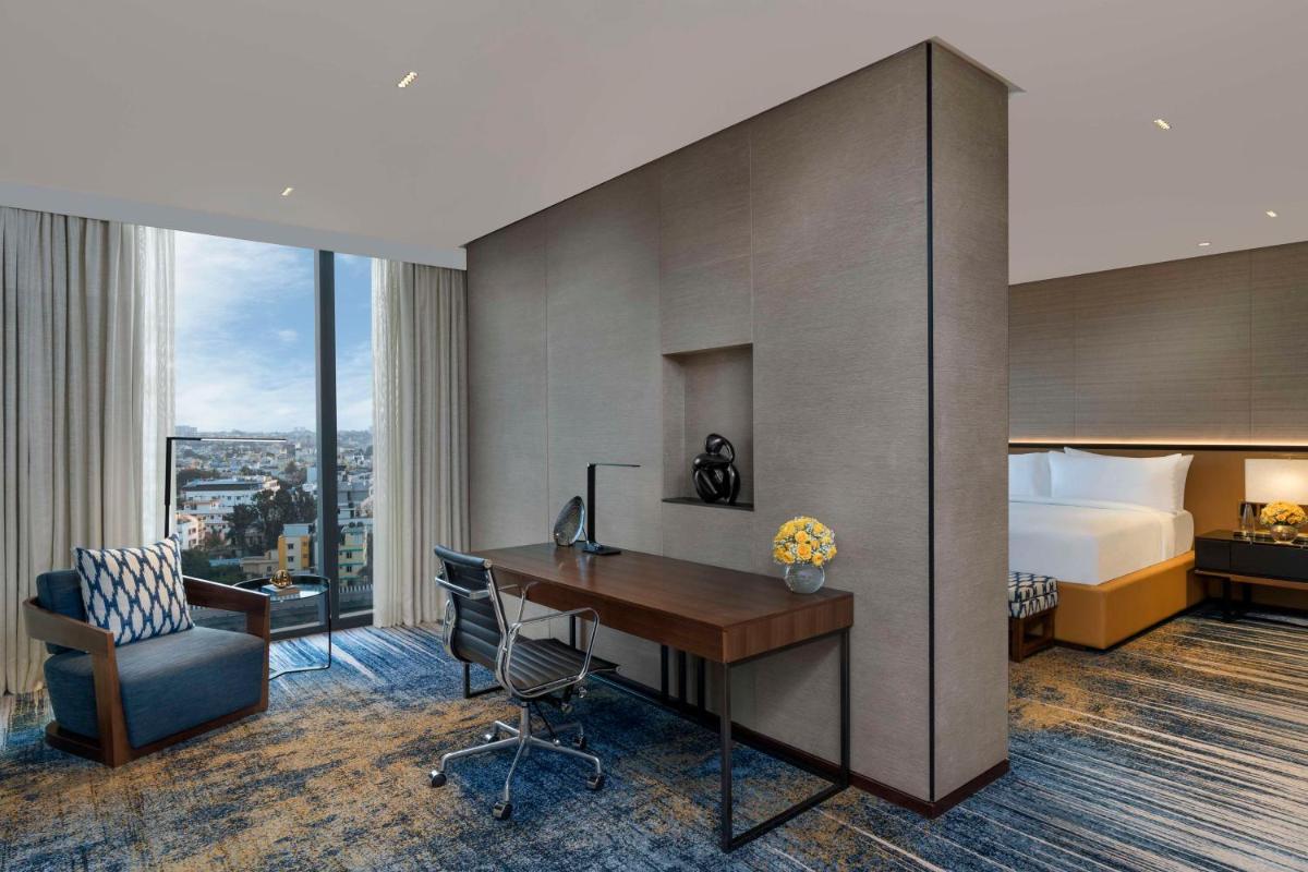 a hotel room with a desk and a bed and a bedroom at Hilton Bengaluru Embassy Manyata Business Park in Bengaluru