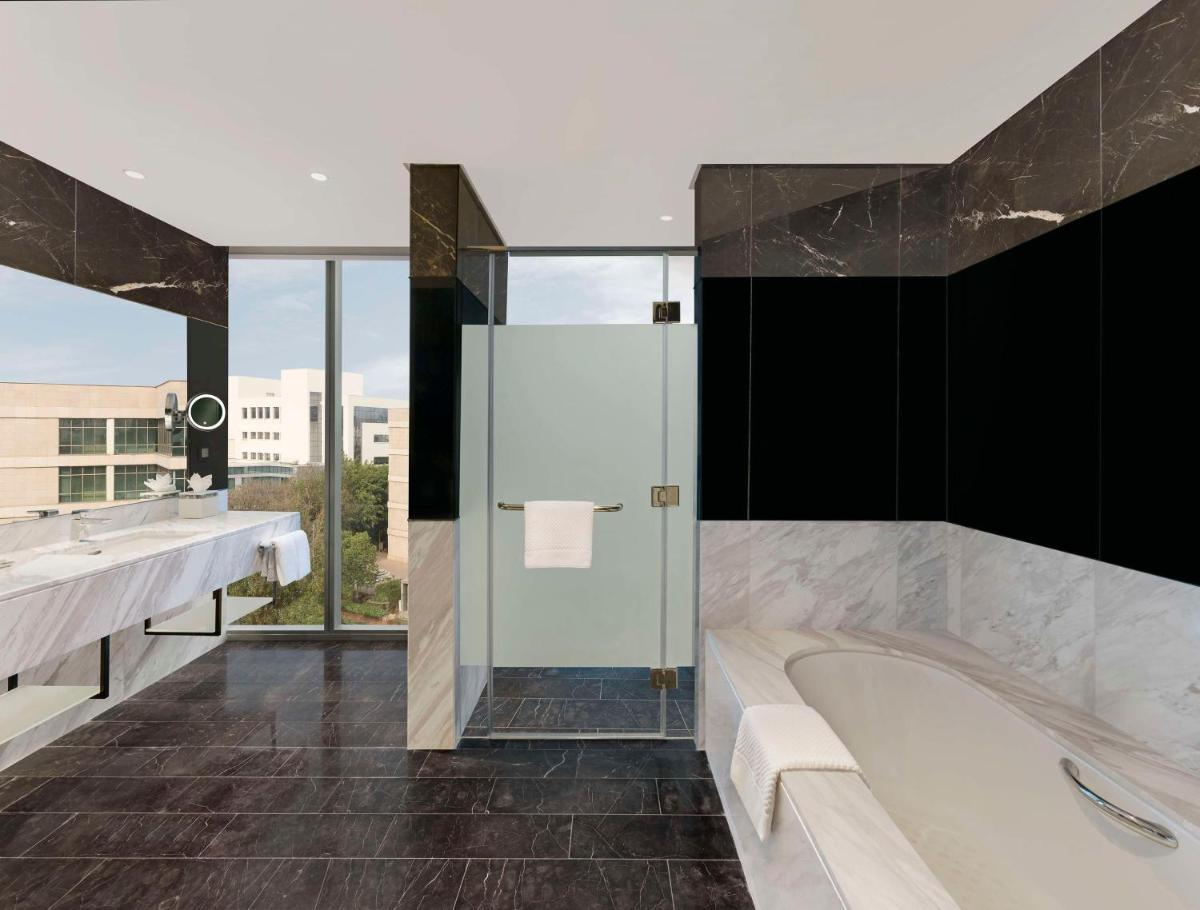 a bathroom with a tub and a large window at Hilton Bengaluru Embassy Manyata Business Park in Bengaluru