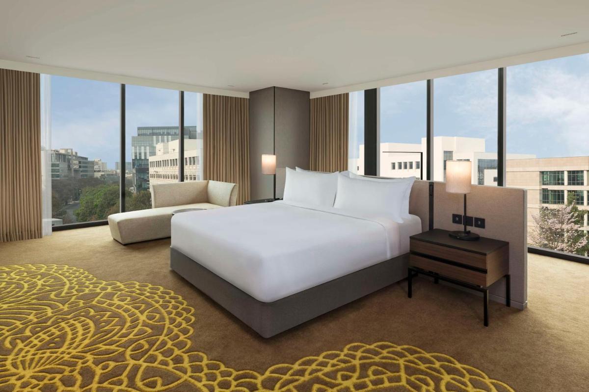 a bedroom with a white bed and a large window at Hilton Bengaluru Embassy Manyata Business Park in Bengaluru