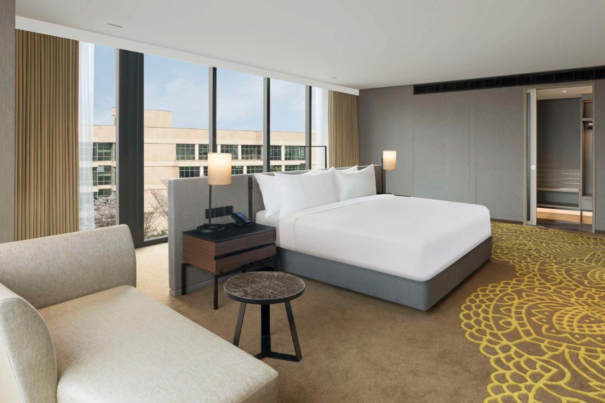 a hotel room with a bed and a couch and chairs at Hilton Bengaluru Embassy Manyata Business Park in Bengaluru