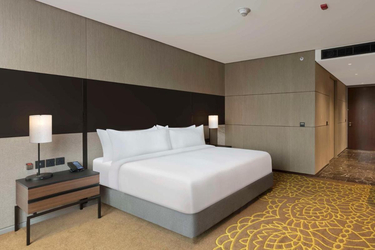 a bedroom with a large white bed and a table at Hilton Bengaluru Embassy Manyata Business Park in Bengaluru