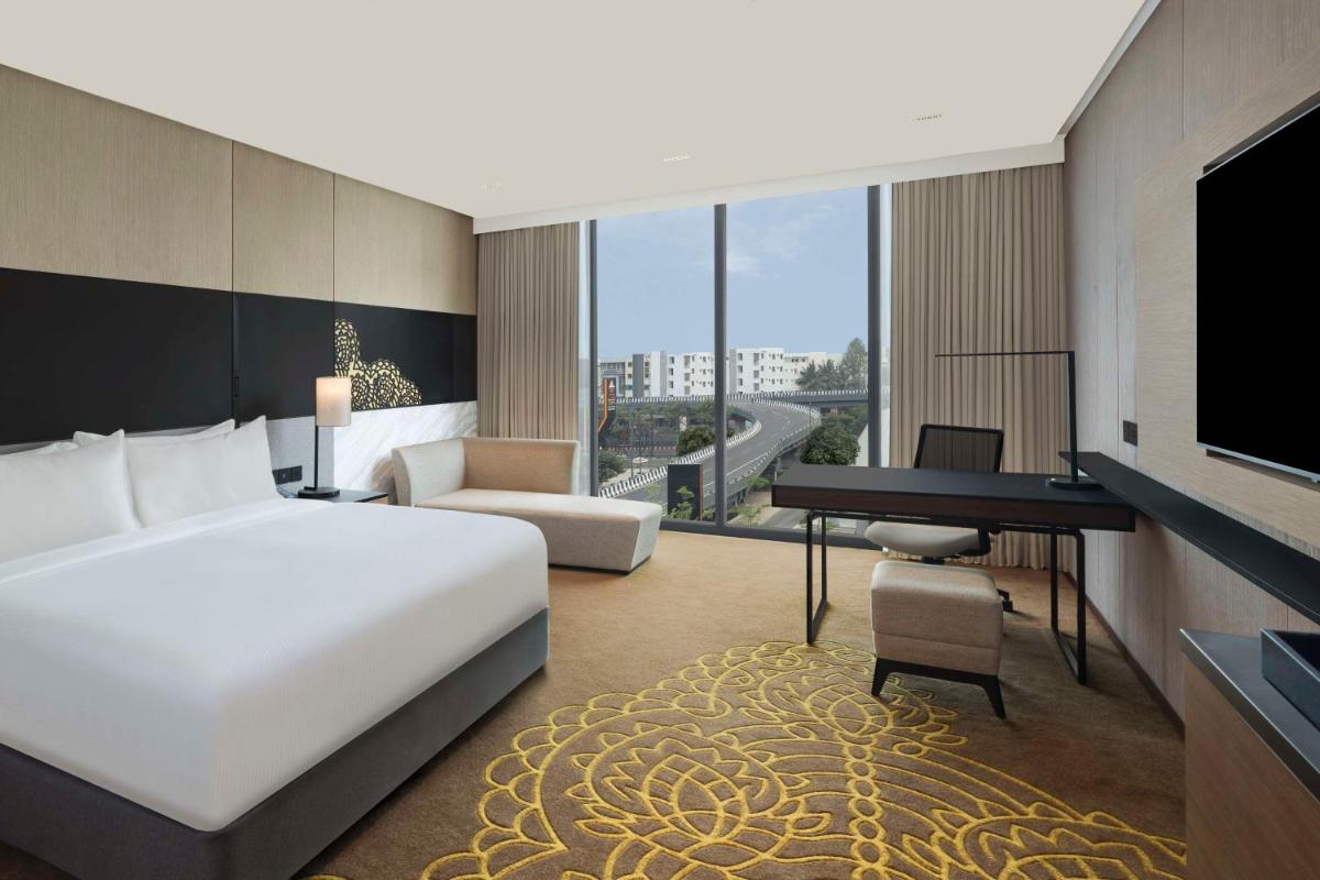 a hotel room with a bed and a desk and a television at Hilton Bengaluru Embassy Manyata Business Park in Bengaluru