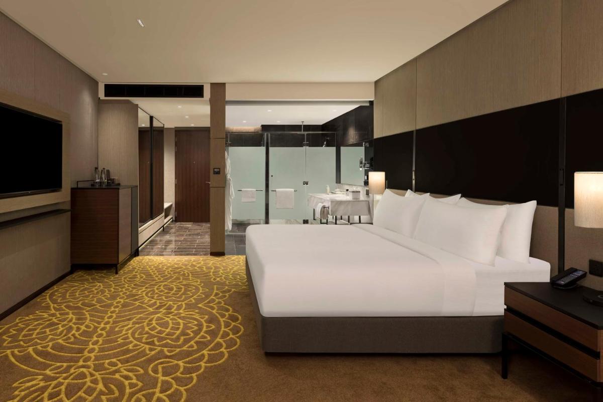a bedroom with a large white bed and a television at Hilton Bengaluru Embassy Manyata Business Park in Bengaluru a bedroom with a large white bed and a television at Hilton Bengaluru Embassy Manyata Business Park in Bengaluru