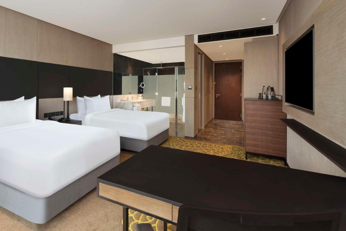 a hotel room with two beds and a bathroom at Hilton Bengaluru Embassy Manyata Business Park in Bengaluru