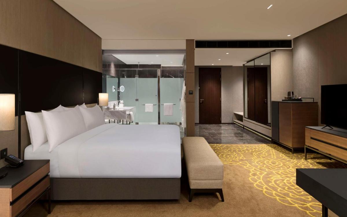 a bedroom with a large white bed and a television at Hilton Bengaluru Embassy Manyata Business Park in Bengaluru