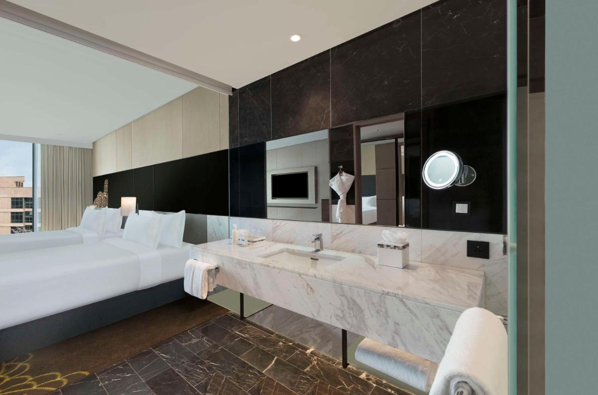 a bathroom with a large white bed and a sink at Hilton Bengaluru Embassy Manyata Business Park in Bengaluru