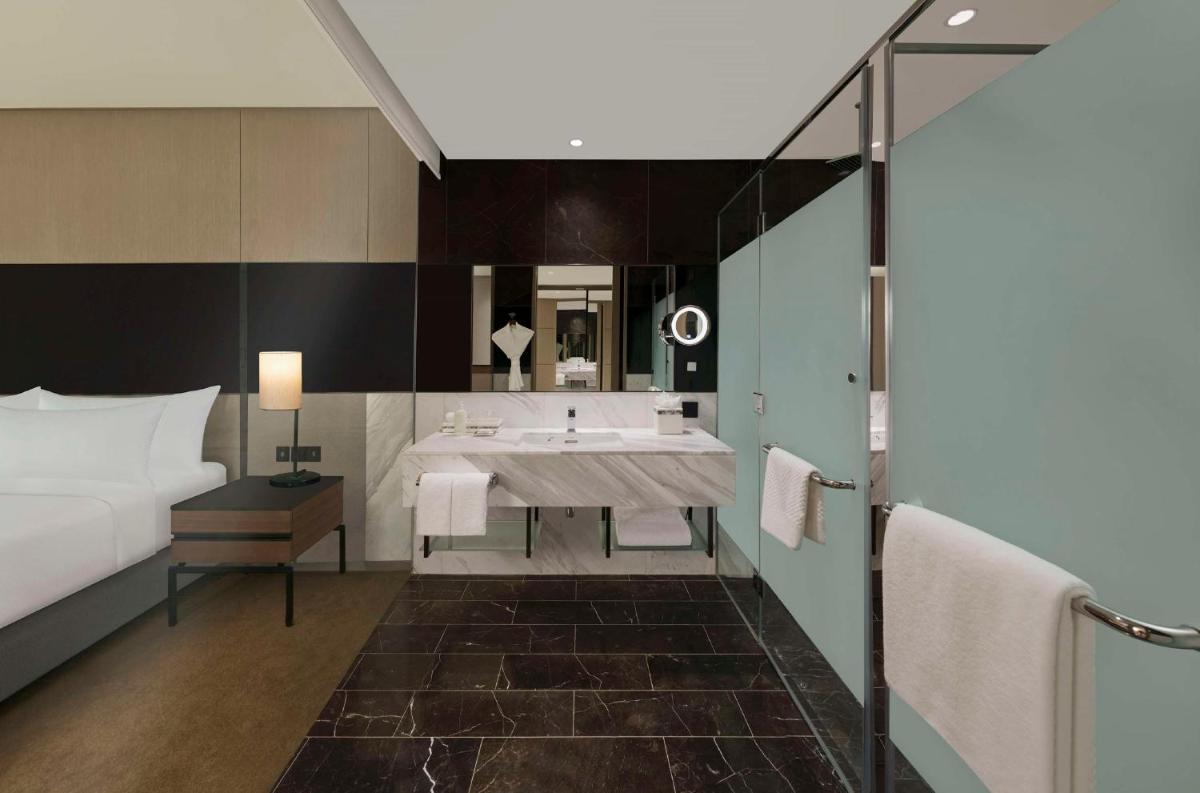 a hotel room with a bathroom with a bed and a sink at Hilton Bengaluru Embassy Manyata Business Park in Bengaluru