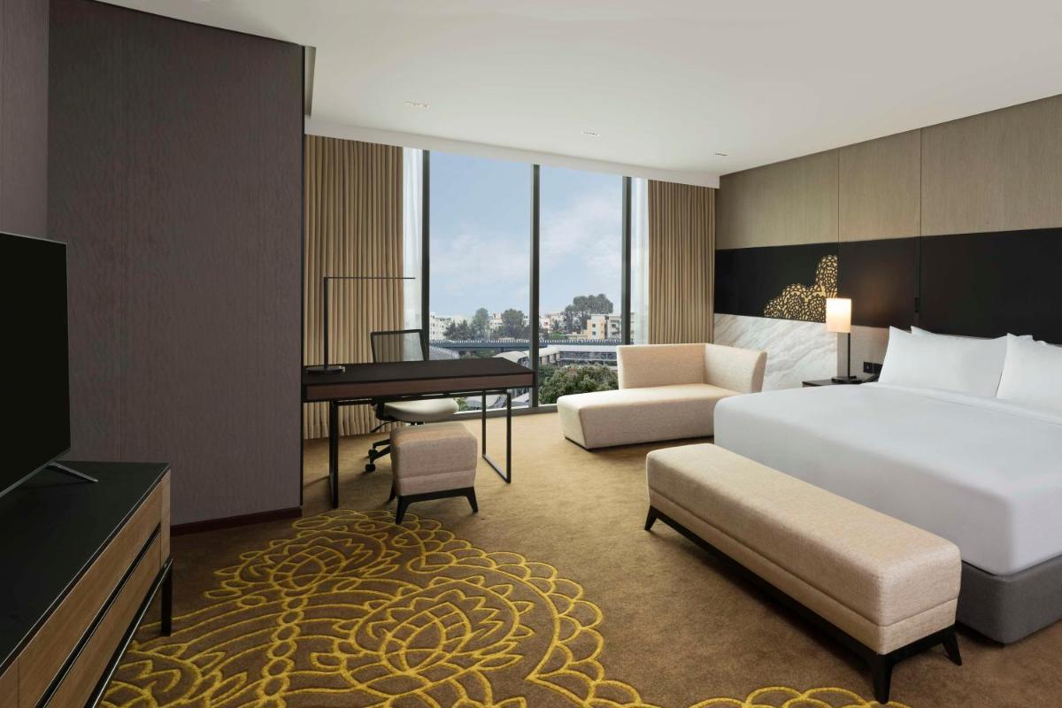 a hotel room with a bed and a desk and a bedroom at Hilton Bengaluru Embassy Manyata Business Park in Bengaluru