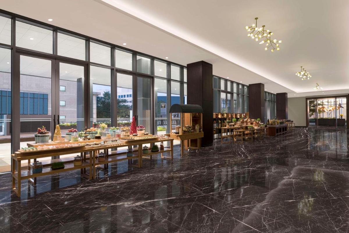 a restaurant with tables and chairs in a room with windows at Hilton Bengaluru Embassy Manyata Business Park in Bengaluru
