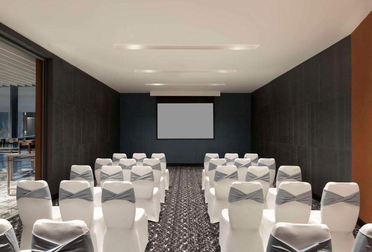 a conference room with white chairs and a screen at Hilton Bengaluru Embassy Manyata Business Park in Bengaluru
