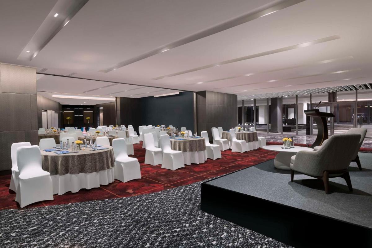 a banquet hall with white tables and white chairs at Hilton Bengaluru Embassy Manyata Business Park in Bengaluru