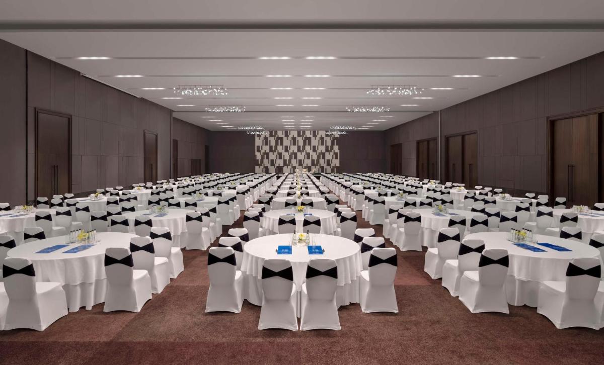 a large banquet hall with white tables and chairs at Hilton Bengaluru Embassy Manyata Business Park in Bengaluru