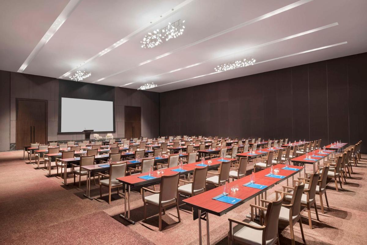 a conference room with tables and chairs and a screen at Hilton Bengaluru Embassy Manyata Business Park in Bengaluru