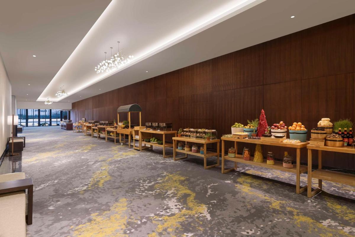 a large room with a row of tables with fruits and vegetables at Hilton Bengaluru Embassy Manyata Business Park in Bengaluru