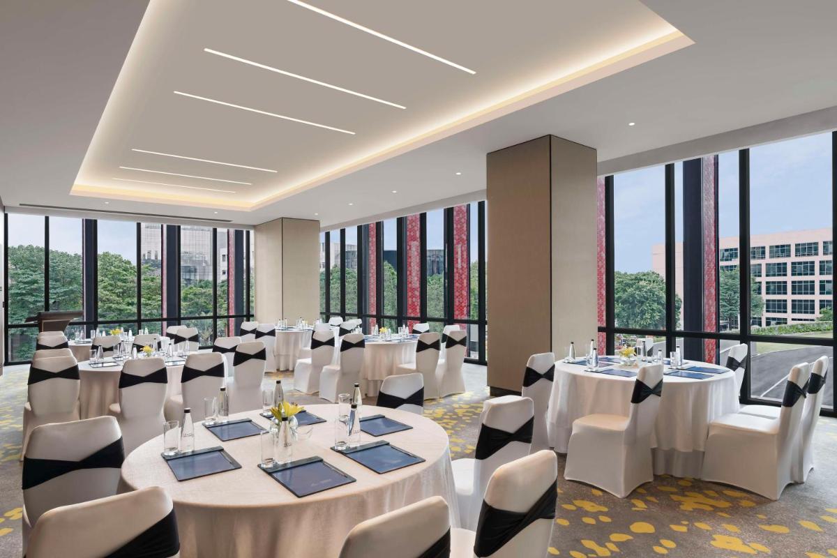 a conference room with white tables and chairs and large windows at Hilton Bengaluru Embassy Manyata Business Park in Bengaluru