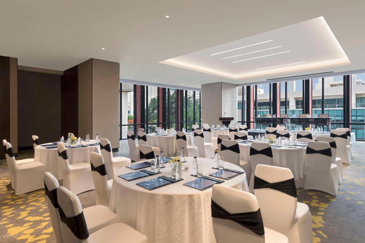 a banquet hall with white tables and white chairs at Hilton Bengaluru Embassy Manyata Business Park in Bengaluru