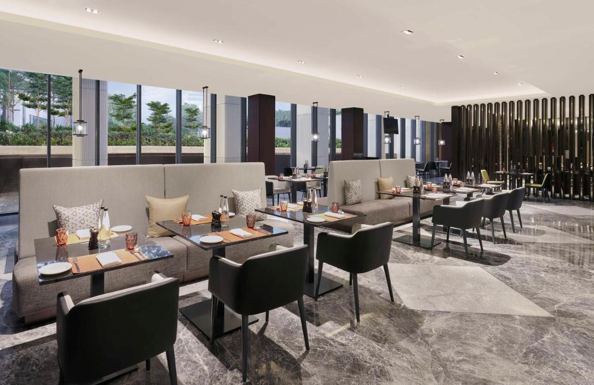 a restaurant with tables and chairs and windows at Hilton Bengaluru Embassy Manyata Business Park in Bengaluru