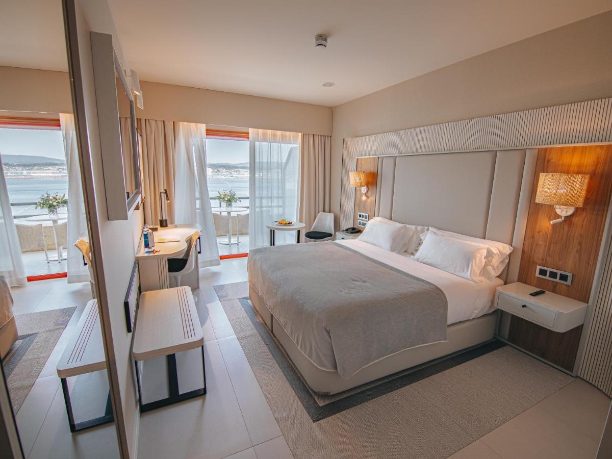 Una habitación de hotel con una cama grande y un escritorio. en Gran Talaso Hotel Sanxenxo, en Sanxenxo