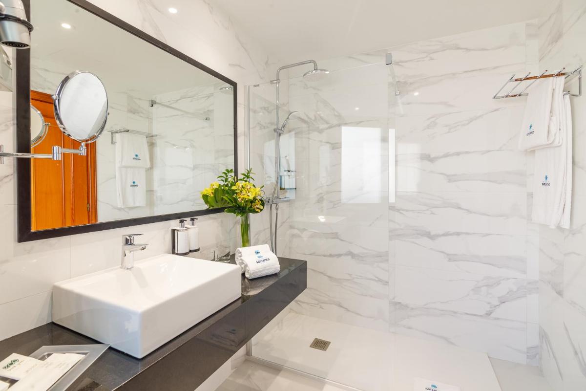 Un baño blanco con lavabo y espejo. en Gran Talaso Hotel Sanxenxo, en Sanxenxo